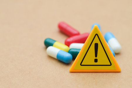 An exclamation mark stands before a pile of colorful capsules, symbolizing the critical importance of drug safety, medical alerts, and awareness of potential side effects.の写真素材