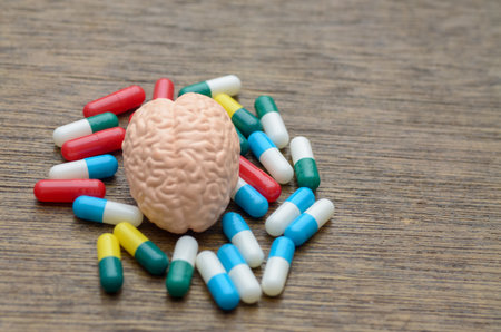 A human brain model surrounded by colorful pills, symbolizing the treatment of neurological and mental health disorders through modern pharmacology.の写真素材