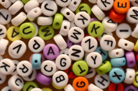 A close-up texture of mixed plastic letter beads, representing the vibrant and complex world of words, language, and education.の写真素材