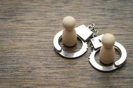 The handcuffs represent joint responsibility and the legal consequences faced by two individuals involved in a transgression.の写真素材