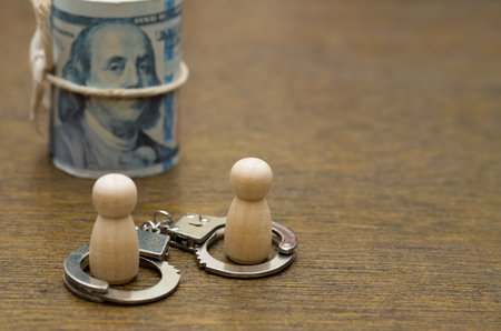 Two figures handcuffed to a roll of money, a powerful metaphor for financial obligation and the loss of freedom.の写真素材