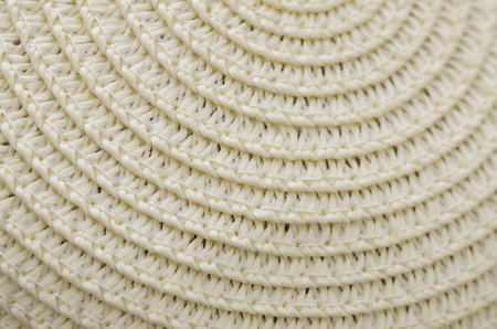A close-up, spiraling pattern of a tightly woven straw hat, showcasing detailed craftsmanship and a rhythmic, tactile surface perfect for summer themes.の写真素材