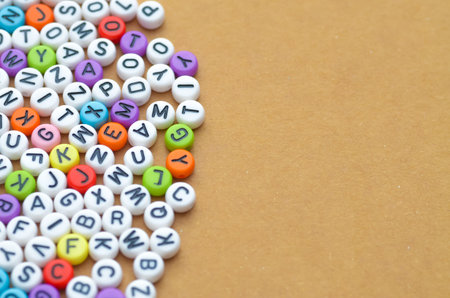 A vibrant pile of colorful letter beads on a wooden surface, with ample copy space for educational and language-related themes.の写真素材