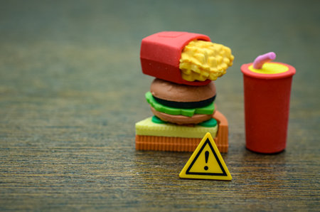 A warning sign in front of junk food, a powerful visual metaphor for the dangers of an unhealthy diet.の写真素材