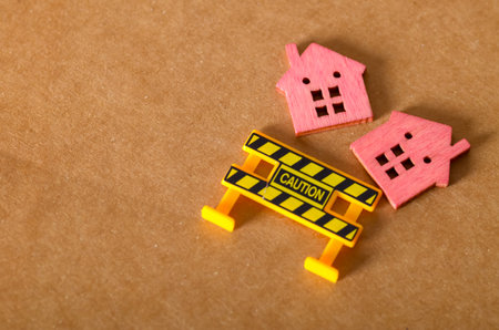 A conceptual image of a fallen model home with a warning barrier, representing a housing market...