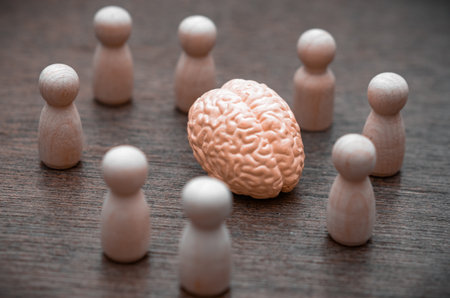 A group of figures surrounds a central brain, symbolizing groupthink, shared knowledge, and...