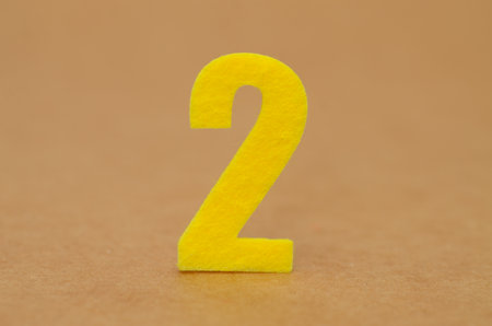 Educational Felt Number 2: A clean and simple setup of a yellow felt number two, ideal for children's learning materials, crafts, or calendarsの写真素材