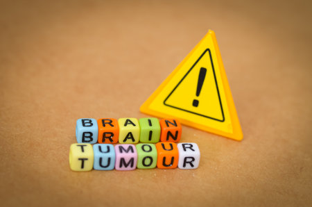 Warning: Brain Tumour. A stark visual featuring text and a yellow warning sign, highlighting the serious medical diagnosis and health risk.の写真素材