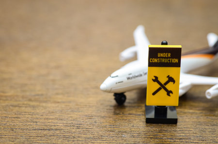 Aircraft Maintenance and Repair: A toy plane and a construction sign with tool icons, representing the aviation industry's service and repair sector.の写真素材