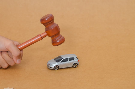 Legal Judgment on Wheels: Gavel Poised Over Toy Car Symbolizing Automotive Law and Court Action.の写真素材