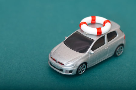 Vehicle Safety and Auto Insurance Metaphor with Miniature Car and Lifebuoyの写真素材
