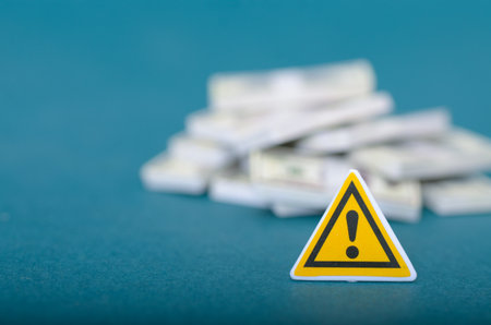 Caution with Money: Yellow Hazard Sign and White Documents or Currency Piles Highlighting Investment Risks and Asset Managementの写真素材