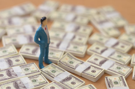 Miniature Business Man Navigating Through Stacks of Cash and Abundanceの写真素材