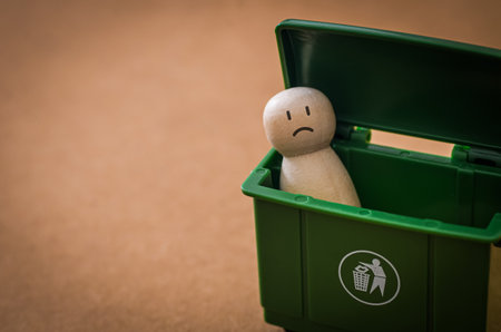 Disposable Humanity: A Sad Peg Doll Inside a Green Waste Container