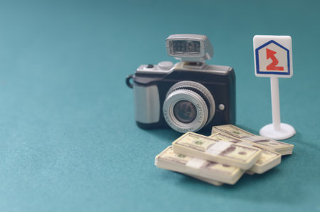 A Miniature Camera and Stacks of Cash on a Teal Background Symbolizing a Successful Photography Career.の写真素材