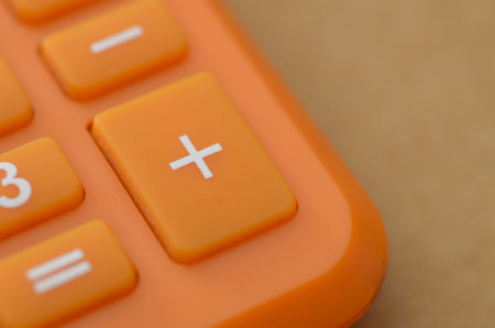 Vibrant Orange Calculator Keypad with Center Focus on Addition Symbol and Soft Bokehの写真素材