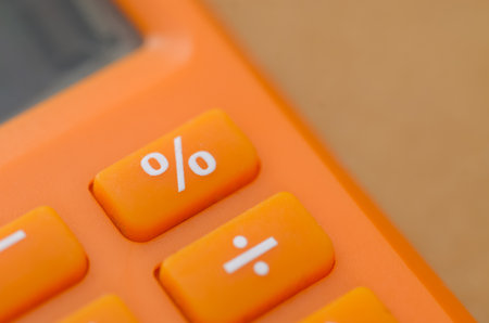 Close-up of Orange Calculator Featuring Percentage and Division Symbolsの写真素材