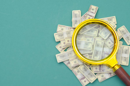 Searching for Wealth: Magnifying Glass Over US Dollar Bills for Financial Auditing