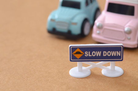 Road Safety and Traffic Control Concept with Miniature Cars and Slow Down Sign