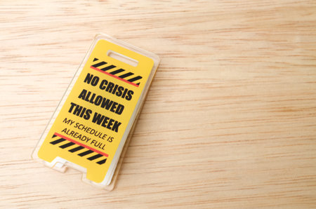 Yellow novelty desk sign with message no crisis allowed this week schedule full