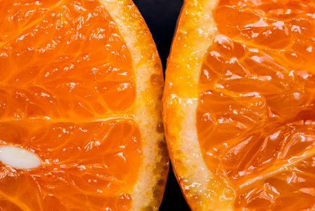 Oranges on a black background. One orange is cut in half close up, the other is whole.の写真素材