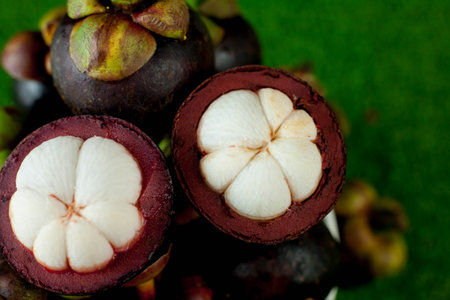 Fresh ripe mangosteen fruits and cross section showing the thick purple skin and white flesh.の写真素材