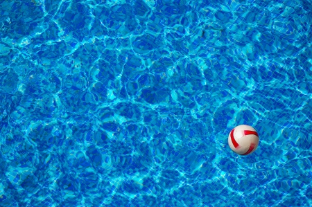 Beach ball floating in the blue clear water of swimming pool with mosaic bottomの写真素材