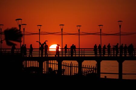 Pier with people relaxing by the sunsetの写真素材