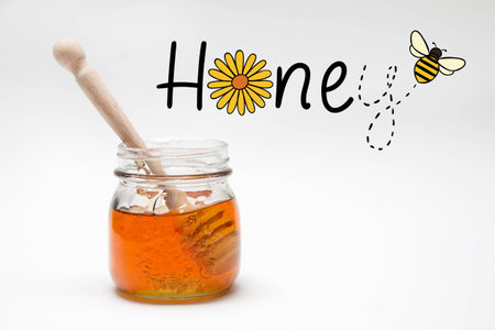 Photo of a honey jar and a honey spoon on a white background with the Honey caption and a bee graphicの写真素材
