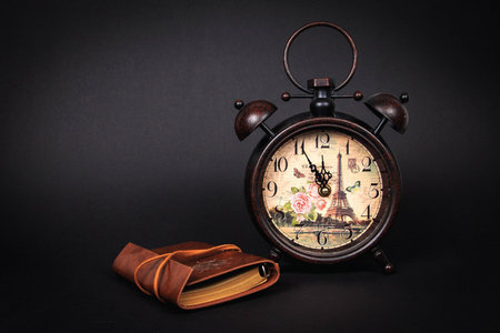 Close up of an old vintage watch with vintage planner on a black background