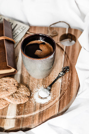 Photo of a coffe, cookies, spoon of sugar and vintage notebook on a wooden boardの写真素材