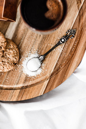 Top view photo of a coffe, cookies and vintage spoon of sugar on a wooden boardの写真素材