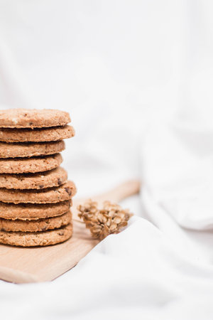Close up of a sweet homemade cookies on a wooden board on a bed sheet