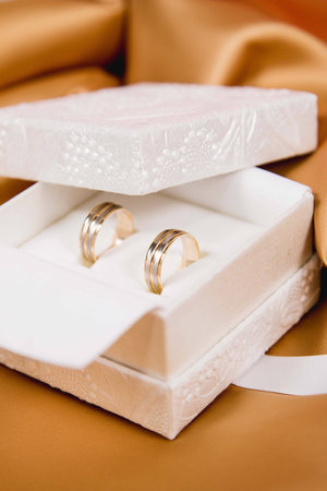 Beautiful close up of wedding rings in white luxury box in yellow shiny backgroundの写真素材