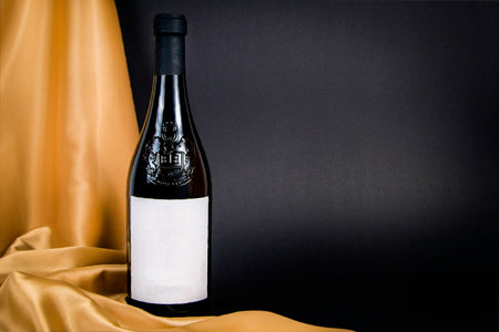 Close up of a bottle of white wine with black background and yellow silkの写真素材