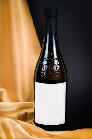 Close up of a white wine bottle with black background and yellow silkの写真素材