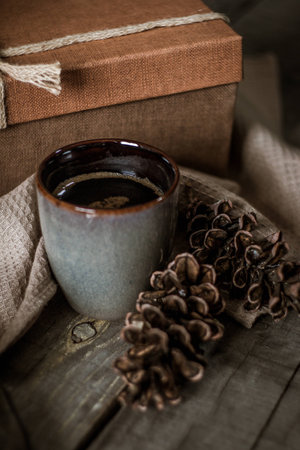 Chocolate birthday cake with flowers, cup of coffee and present box on a wooden tableの写真素材