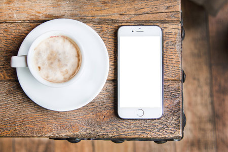 To view of a fresh coffee and a mobile phone template on a wooden tableの写真素材