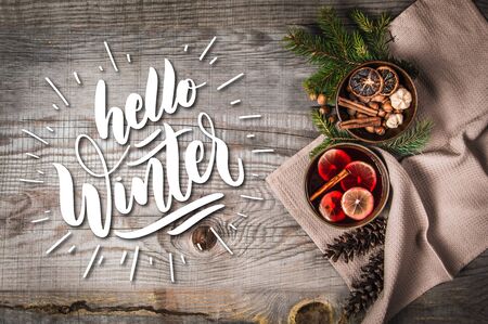 Fruit tea with cinnamon and lemon and decoration on a wooden background with text Hello Winterの写真素材