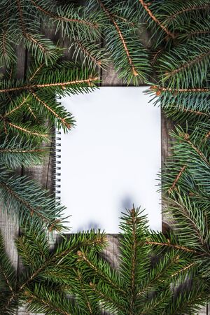 White paper sheet surrounded with pine tree branchesの写真素材