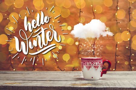 Holiday mug with snowing cloud and bokeh lights on a wooden tableの写真素材