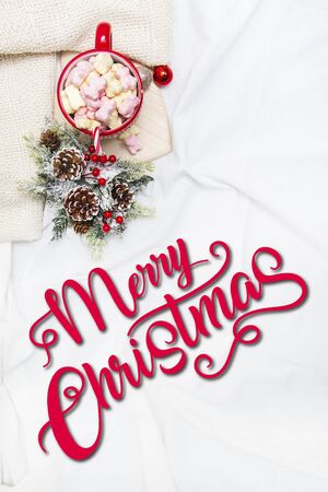 Red mug with marshmallows and winter ornaments on a white sheets with text Merry Christmas  Tの写真素材