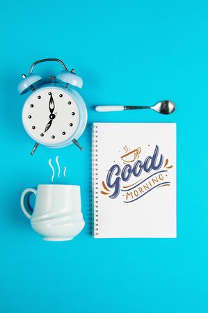 Coffee mug with notebook and clock with quote Good Morningの写真素材