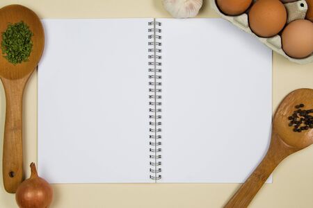 Wooden ladles with spices, eggs and garlic with a blank notebook pageの写真素材