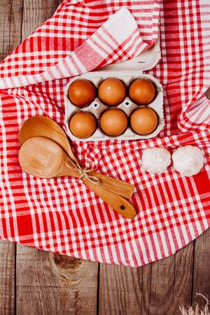 Wooden ladles and eggs on a red and white table rugの写真素材