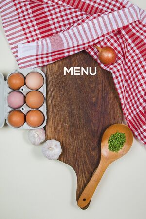 Wooden cutting board with food spices, spoon, eggs and garlicsの写真素材