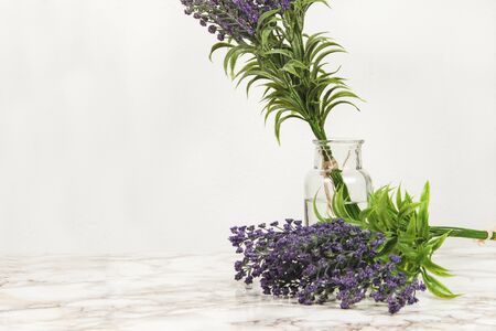 Lavender flowers in a glass vase on a marble tableの写真素材