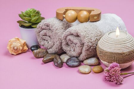 Spa essentials, aroma sticks stones, towels and a plant on a pink backgroundの写真素材