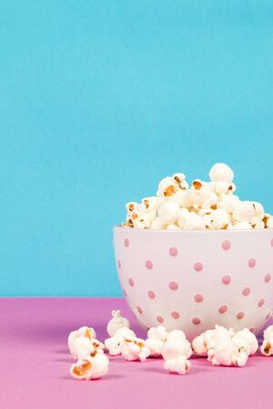 Fresh popcorn in a white pink bowl on pink and blue backgroundの写真素材