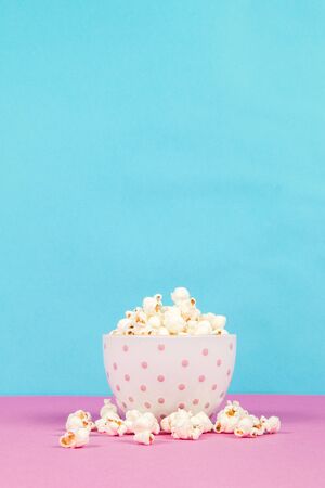 Fresh popcorn in a white pink bowl on pink and blue backgroundの写真素材